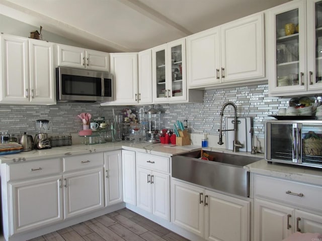 kitchen featuring tasteful backsplash, light stone countertops, sink, and white cabinets