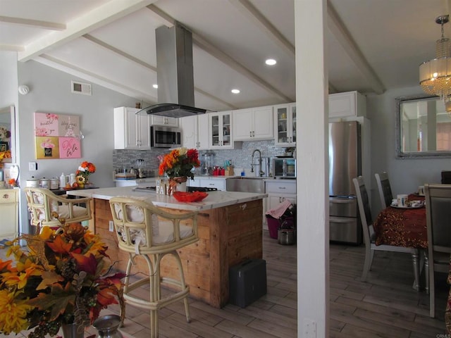 kitchen featuring island range hood, sink, white cabinets, and lofted ceiling with beams