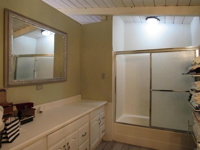 bathroom featuring vanity, beam ceiling, hardwood / wood-style flooring, wooden ceiling, and enclosed tub / shower combo