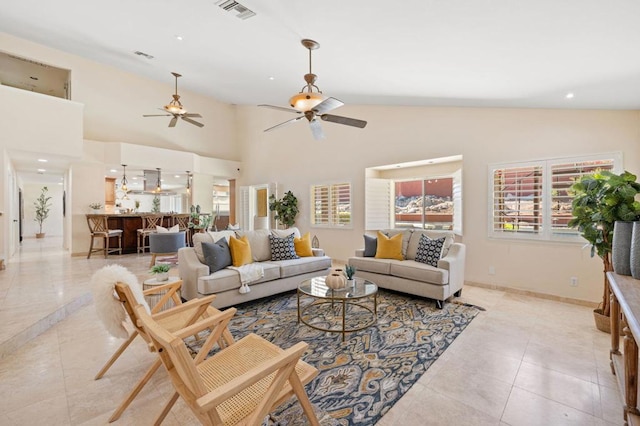 living room featuring ceiling fan, a high ceiling, and light tile patterned floors