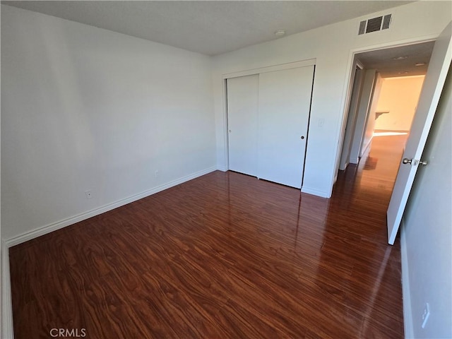 unfurnished bedroom featuring dark hardwood / wood-style flooring and a closet