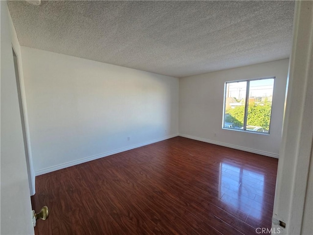 empty room with a textured ceiling and dark wood-type flooring