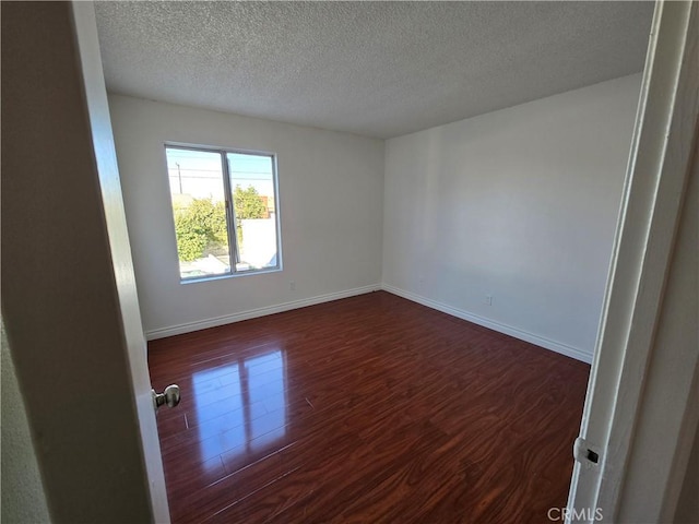 unfurnished room with a textured ceiling and dark wood-type flooring