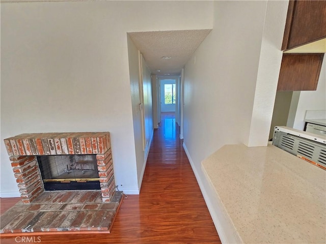 corridor featuring a textured ceiling and dark hardwood / wood-style flooring