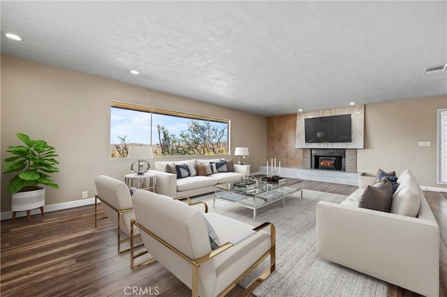 living room featuring a fireplace, wood-type flooring, and a textured ceiling