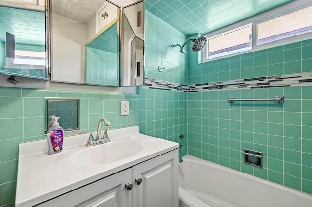 bathroom featuring plenty of natural light, tile walls, vanity, and tiled shower / bath combo