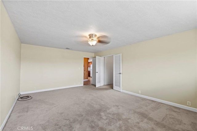 spare room featuring carpet, ceiling fan, and a textured ceiling