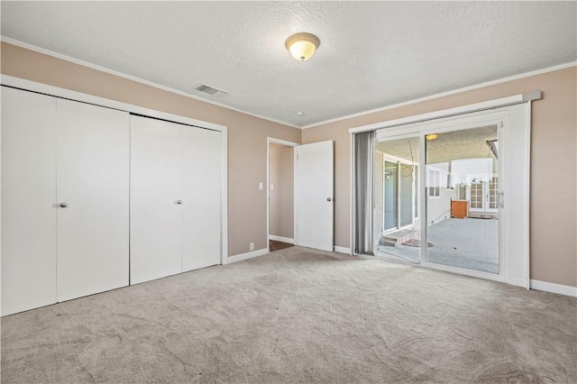 unfurnished bedroom with crown molding, a textured ceiling, access to outside, a closet, and carpet