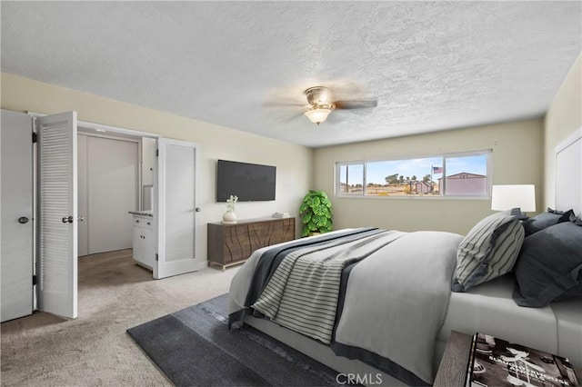 bedroom featuring ceiling fan, light colored carpet, and a textured ceiling