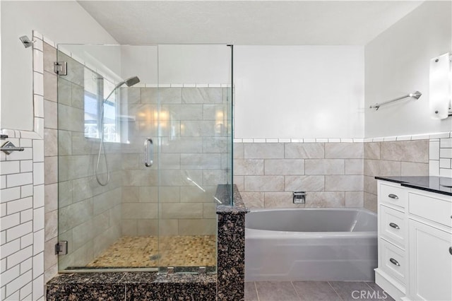 bathroom with tile patterned floors, vanity, separate shower and tub, and tile walls