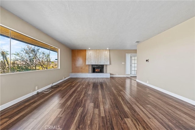 unfurnished living room featuring a textured ceiling, a fireplace, and dark hardwood / wood-style floors