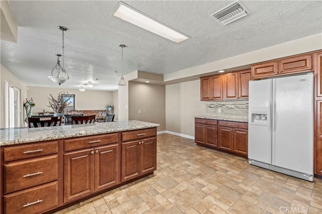 kitchen with white refrigerator with ice dispenser, decorative backsplash, light stone countertops, a textured ceiling, and decorative light fixtures