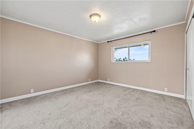 carpeted empty room with ornamental molding and a textured ceiling