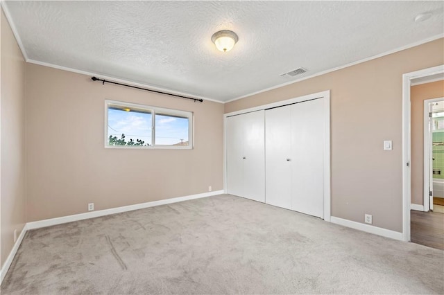 unfurnished bedroom with ornamental molding, a textured ceiling, light carpet, and a closet