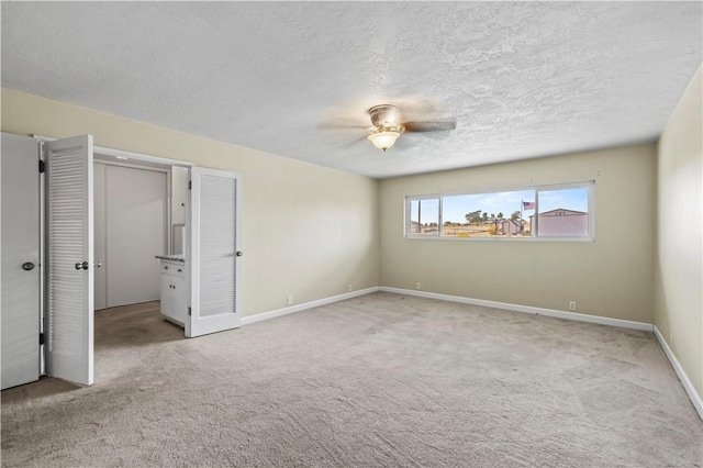 unfurnished bedroom with a textured ceiling, light colored carpet, and ceiling fan