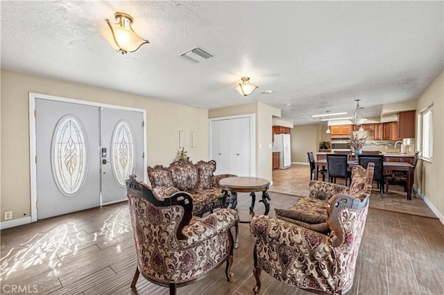 living room with light hardwood / wood-style floors, a textured ceiling, and a wealth of natural light