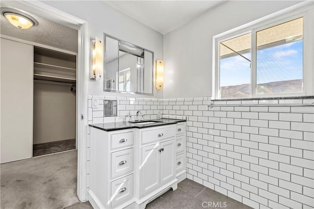 bathroom with vanity, a mountain view, tile patterned flooring, a textured ceiling, and tile walls