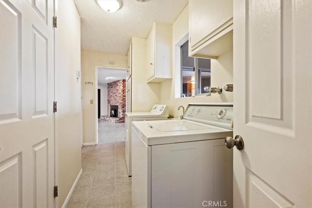 laundry area with washer and clothes dryer, light tile patterned flooring, cabinets, and a textured ceiling