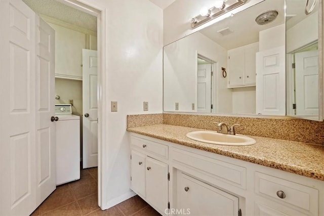 bathroom featuring tile patterned flooring, vanity, and washer / dryer