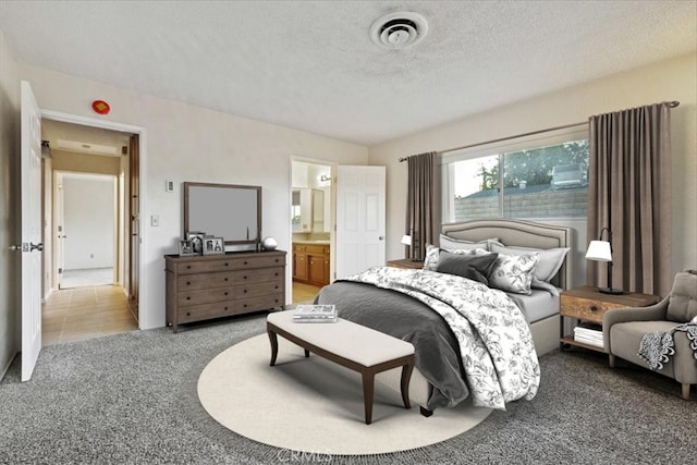 carpeted bedroom featuring ensuite bathroom and a textured ceiling