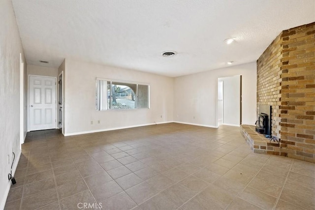 unfurnished living room with a wood stove, tile patterned flooring, and a textured ceiling