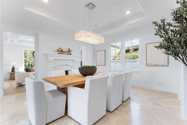 dining area with a tray ceiling, an inviting chandelier, and crown molding