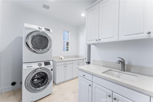 laundry room featuring cabinets, sink, light tile patterned flooring, and stacked washing maching and dryer