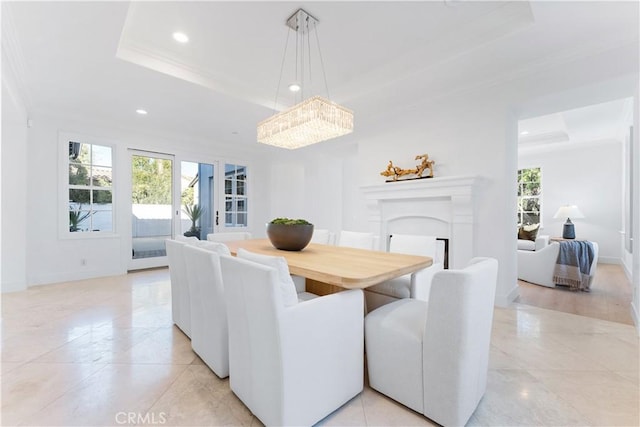 dining room with a tray ceiling, light hardwood / wood-style floors, ornamental molding, and a notable chandelier