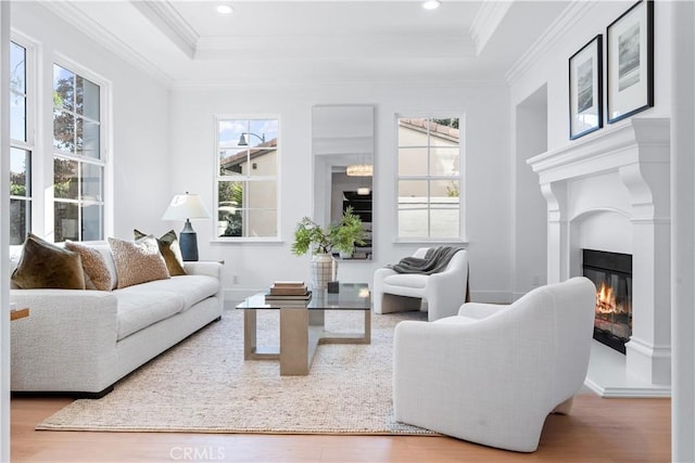 living room featuring crown molding, a healthy amount of sunlight, and light wood-type flooring