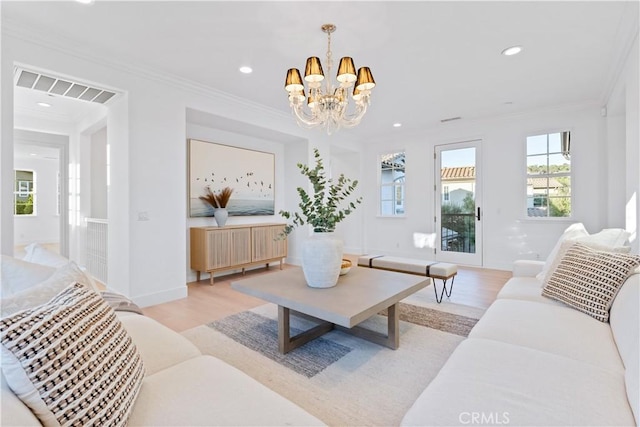 living room with ornamental molding, light hardwood / wood-style flooring, and a notable chandelier