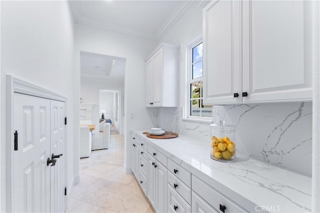 interior space with backsplash, white cabinetry, crown molding, and light stone countertops