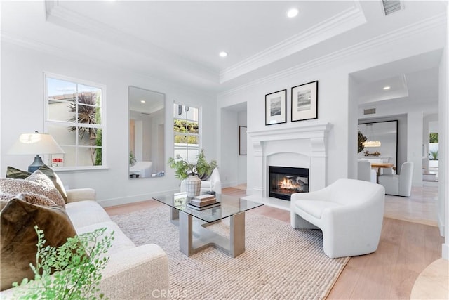 living room featuring a tray ceiling, light hardwood / wood-style flooring, and ornamental molding