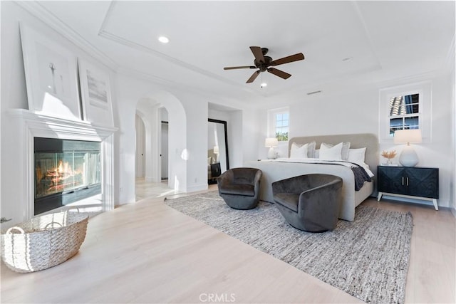 bedroom featuring ceiling fan, light hardwood / wood-style floors, and a tray ceiling