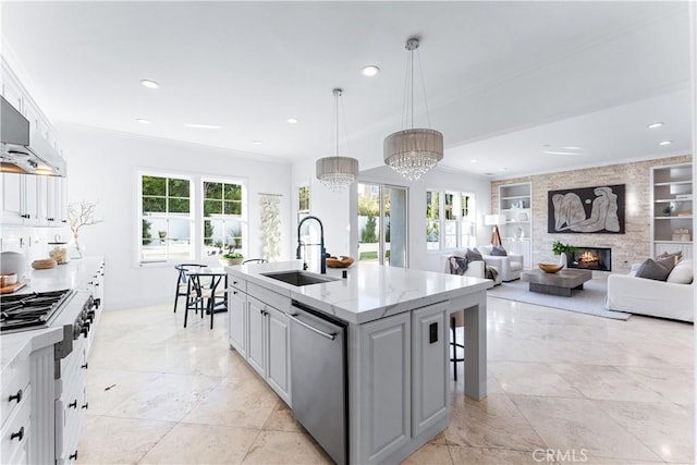 kitchen with stainless steel appliances, sink, a chandelier, hanging light fixtures, and an island with sink