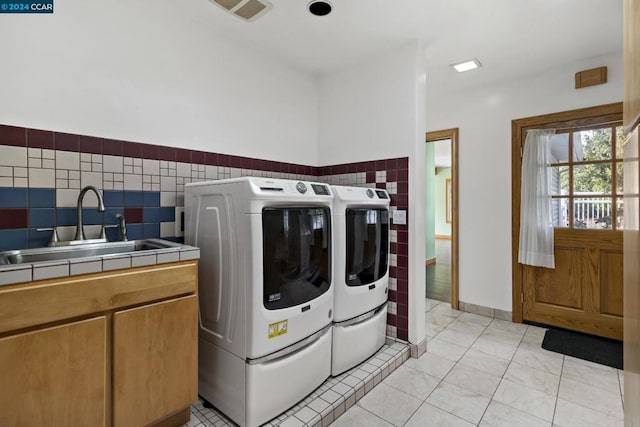 laundry area with washing machine and dryer, sink, light tile patterned floors, and tile walls