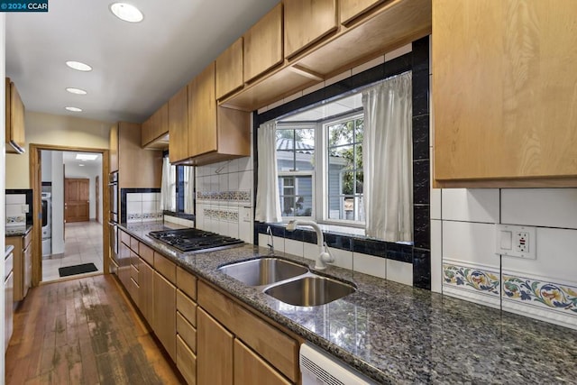 kitchen with dark stone counters, sink, dark hardwood / wood-style floors, tasteful backsplash, and stainless steel gas cooktop