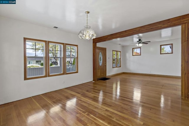 unfurnished room featuring ceiling fan with notable chandelier and light wood-type flooring