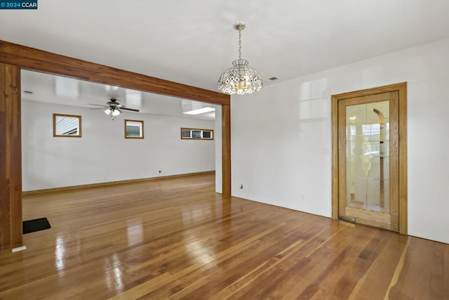 spare room featuring hardwood / wood-style floors and ceiling fan with notable chandelier