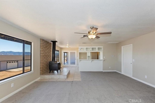 unfurnished living room with a mountain view, light carpet, and a wood stove