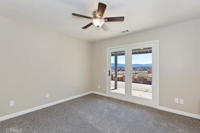 empty room featuring a mountain view, carpet, and ceiling fan