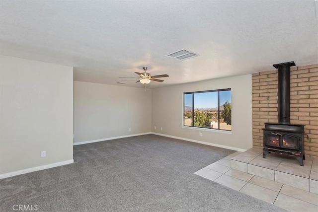 unfurnished living room featuring ceiling fan, carpet floors, and a wood stove