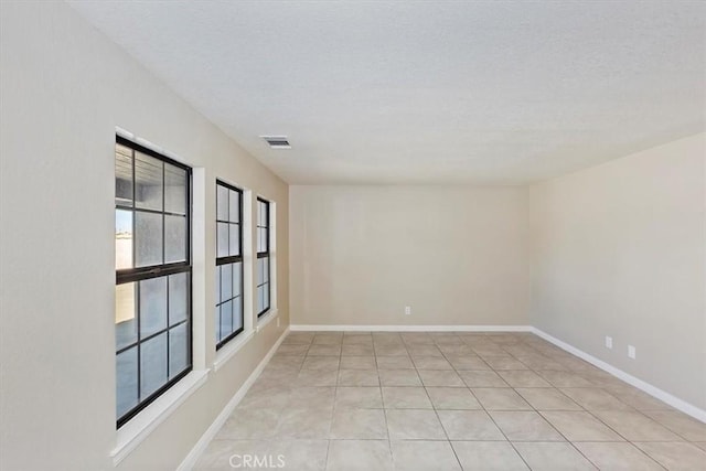 tiled empty room featuring a textured ceiling