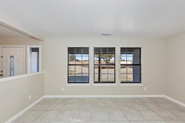 spare room with light tile patterned floors, a textured ceiling, and plenty of natural light