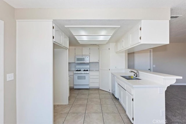 kitchen with white appliances, sink, light tile patterned floors, white cabinetry, and kitchen peninsula