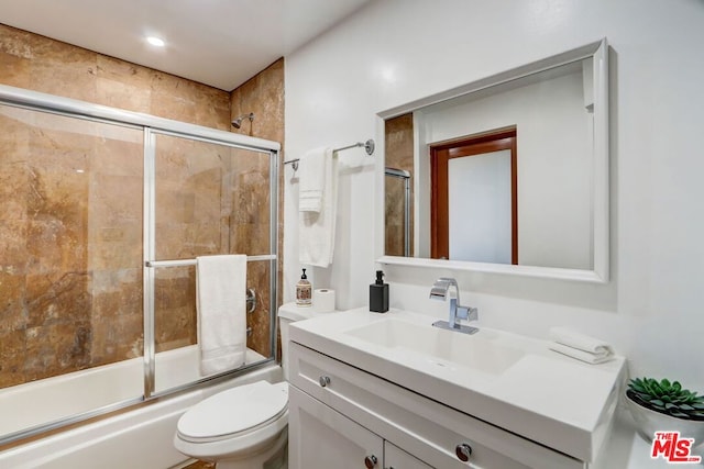 full bathroom featuring vanity, enclosed tub / shower combo, and toilet