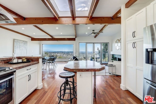 kitchen featuring a kitchen breakfast bar, white cabinetry, a kitchen island, and ceiling fan