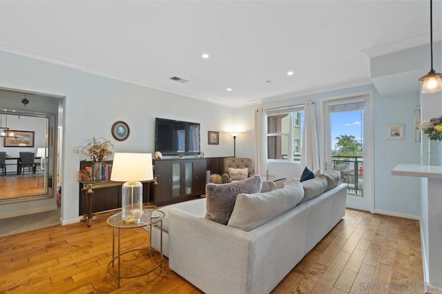 living room with crown molding and light hardwood / wood-style floors