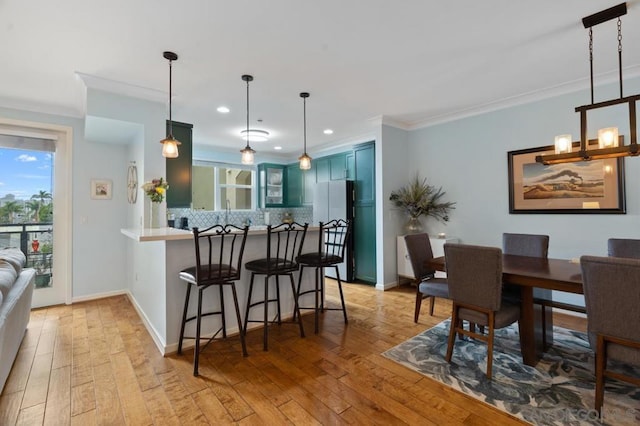 kitchen with blue cabinets, a breakfast bar, refrigerator, hanging light fixtures, and kitchen peninsula