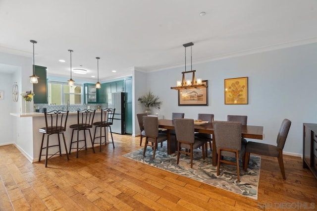 dining room with crown molding, an inviting chandelier, and light hardwood / wood-style flooring