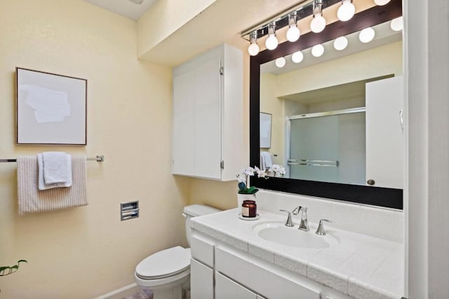 bathroom featuring vanity, toilet, and a shower with door